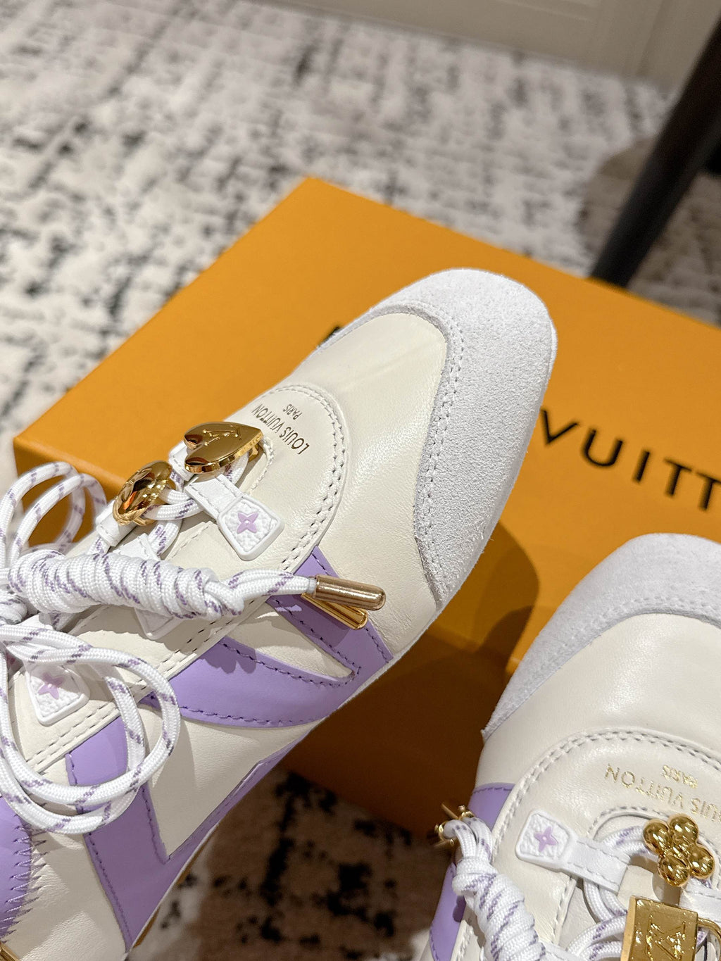 Louis Vuitton sneaker side detail in white with lavender stripe and gold charm on lace-up