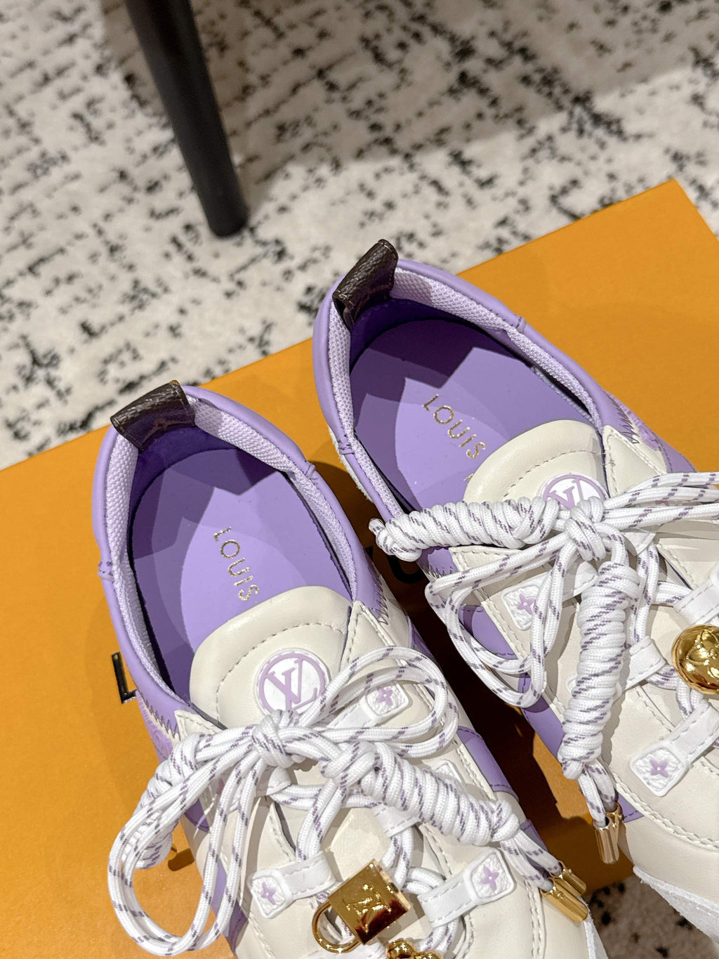 Top view of two Louis Vuitton lace-up sneakers in white with lavender lining and gold emblem