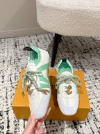 Pair of white-and-mint lace-up sneakers with gold hardware, on a shoebox