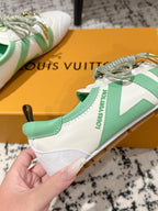 Side view of white sneakers with mint-green side panel and gold logo detail