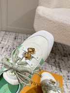 Close-up of white low-top sneakers with mint lining and gold emblem charm on lace