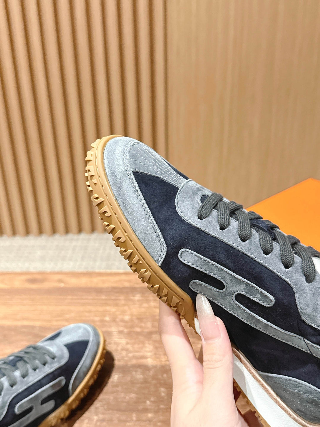 Hermes unisex sneaker close-up, navy and light blue suede with lace-up panel and sole
