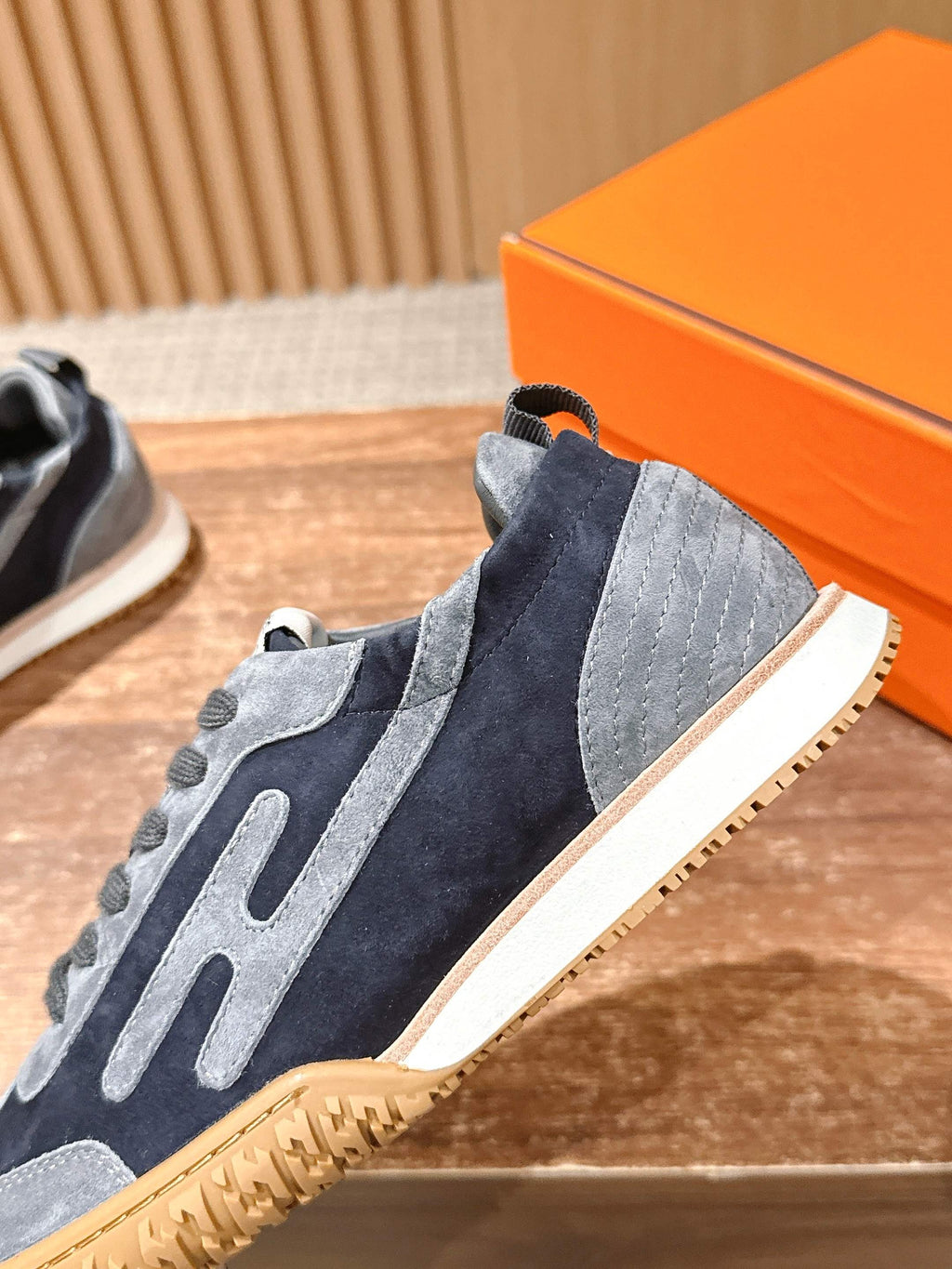 Hermes unisex sneaker close-up at heel, navy and light blue suede with lace-up tabs