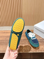 Teal low-top sneaker showing textured yellow outsole, matching navy upper and laces