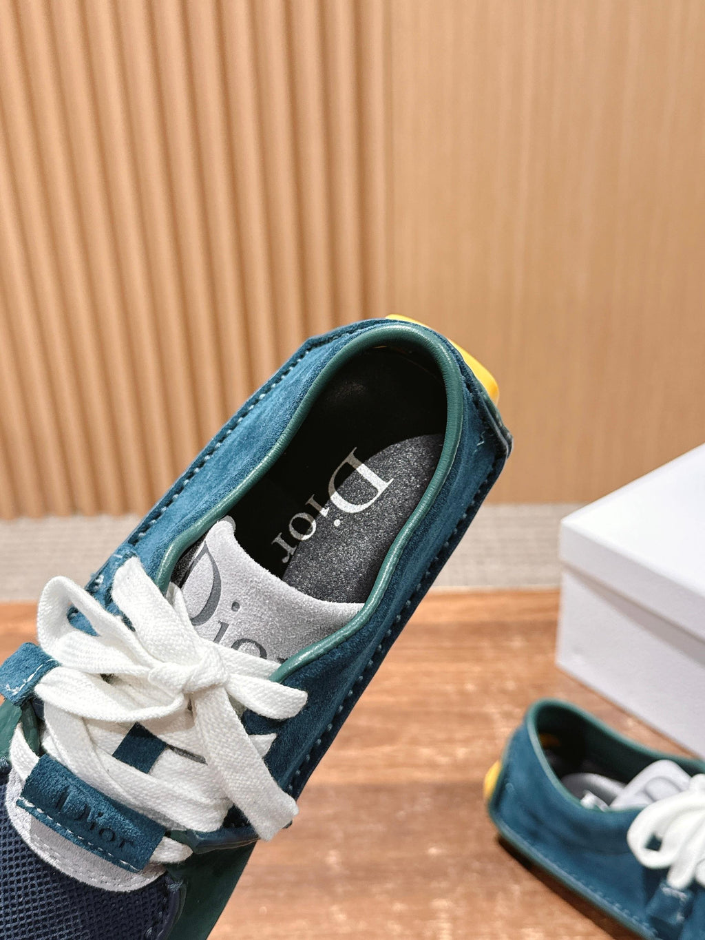 Teal and navy low-top sneaker close-up with white laces and Dior-style lining