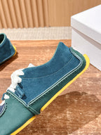 Teal and navy low-top sneaker with white laces and bright yellow sole edge