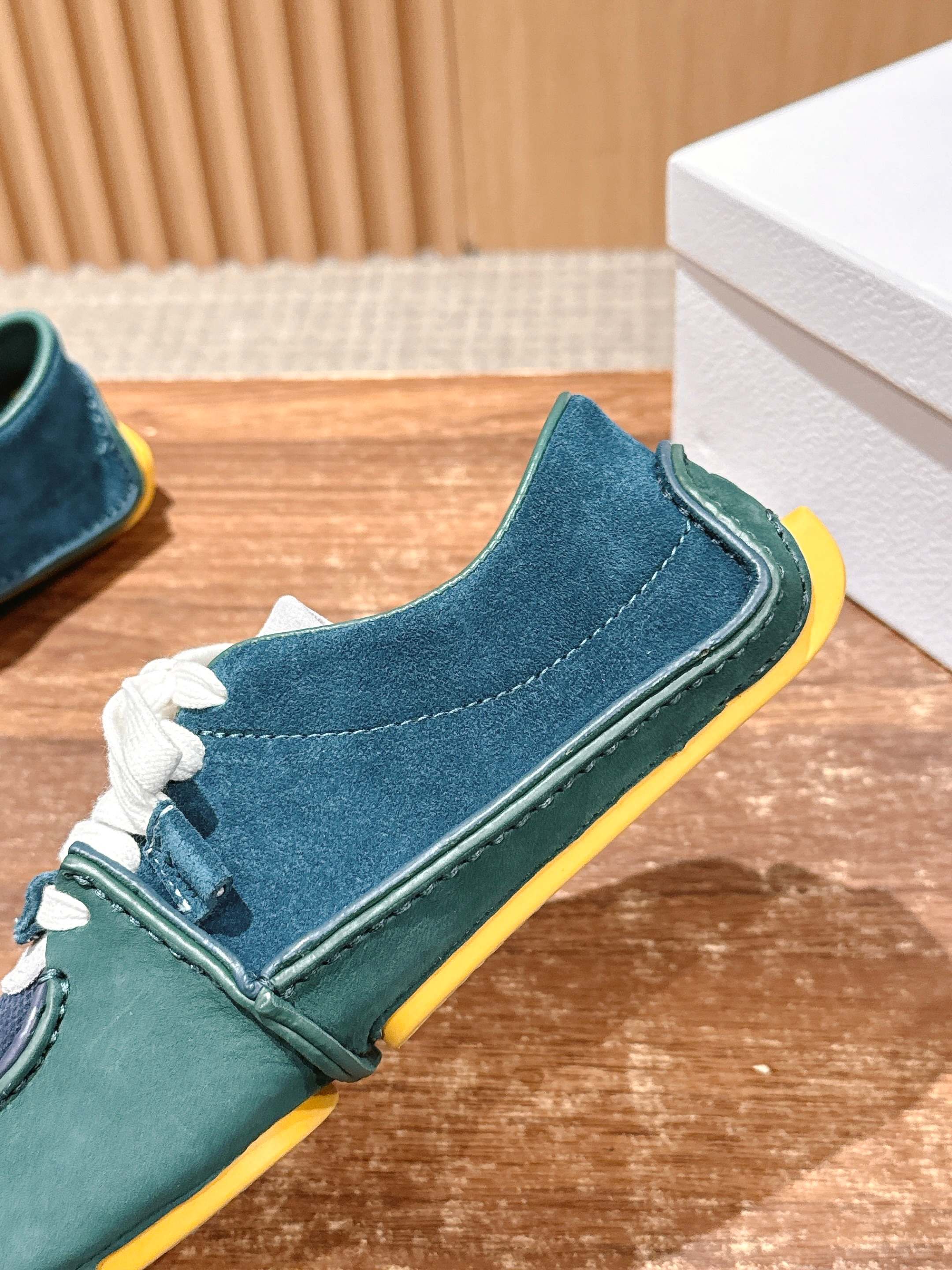 Teal and navy low-top sneaker with white laces and bright yellow sole edge