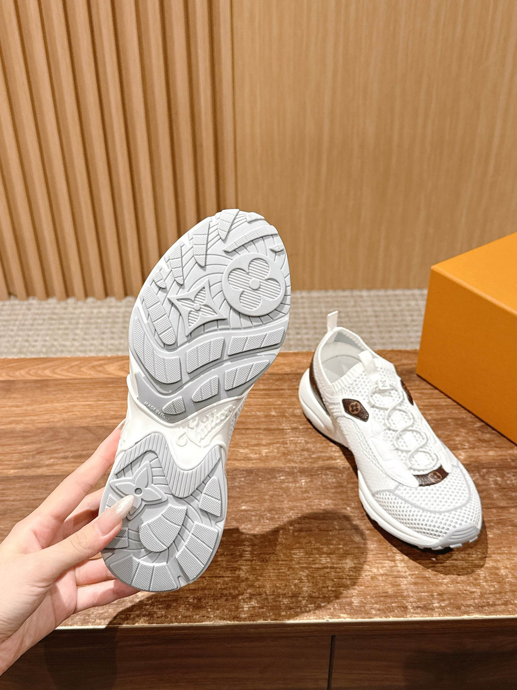 Louis Vuitton unisex sneakers, one showing textured tread sole and white upper with logo patch
