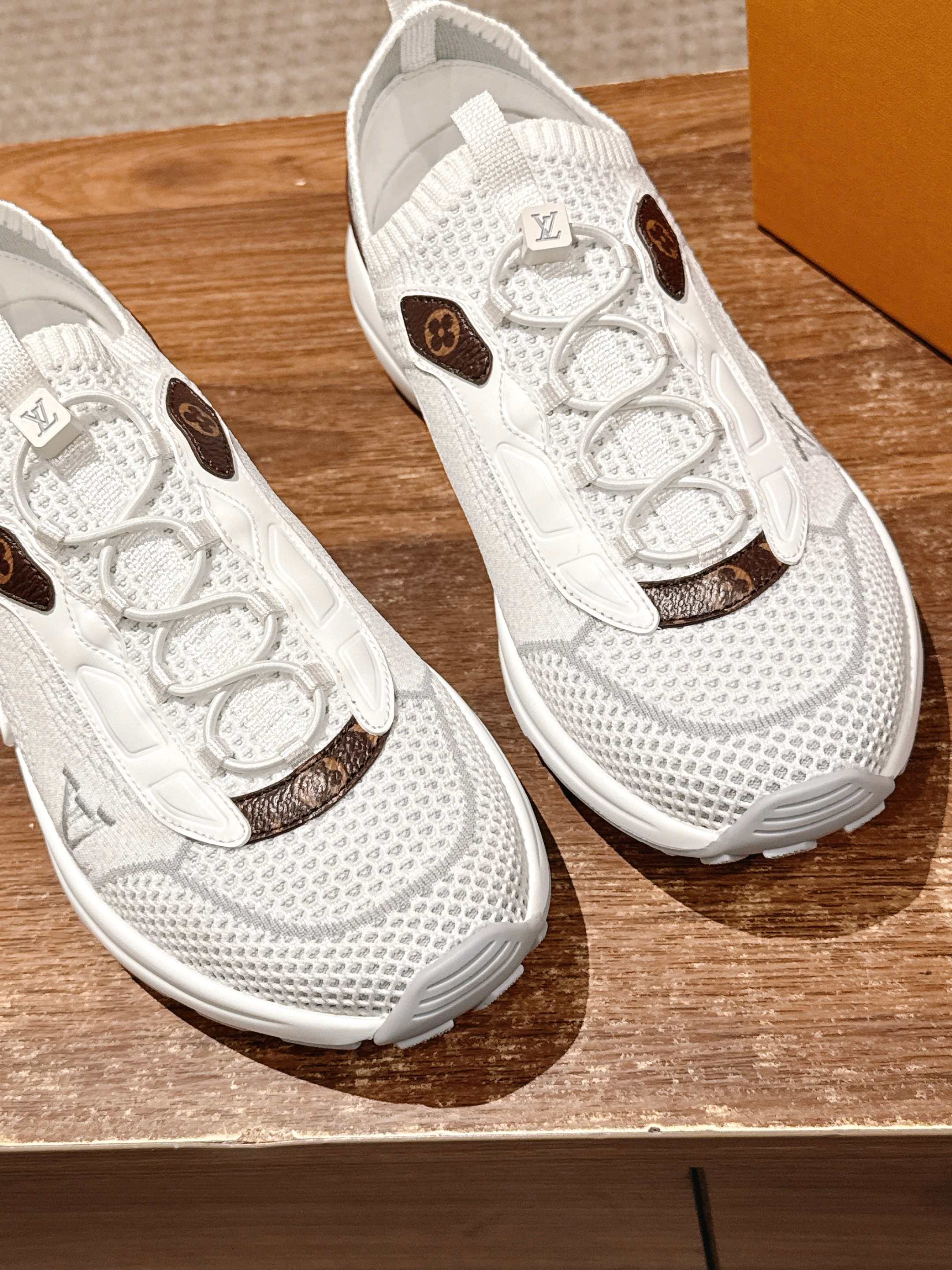 Louis Vuitton unisex white sneakers close-up showing lace eyelets and brown logo patches