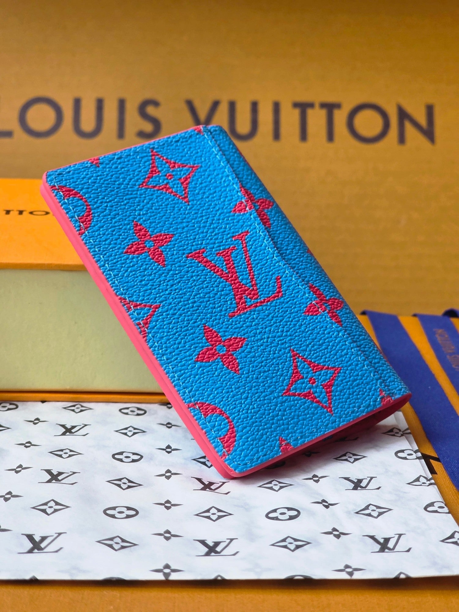 Small bag in bright blue with red monogram-style pattern, close-up