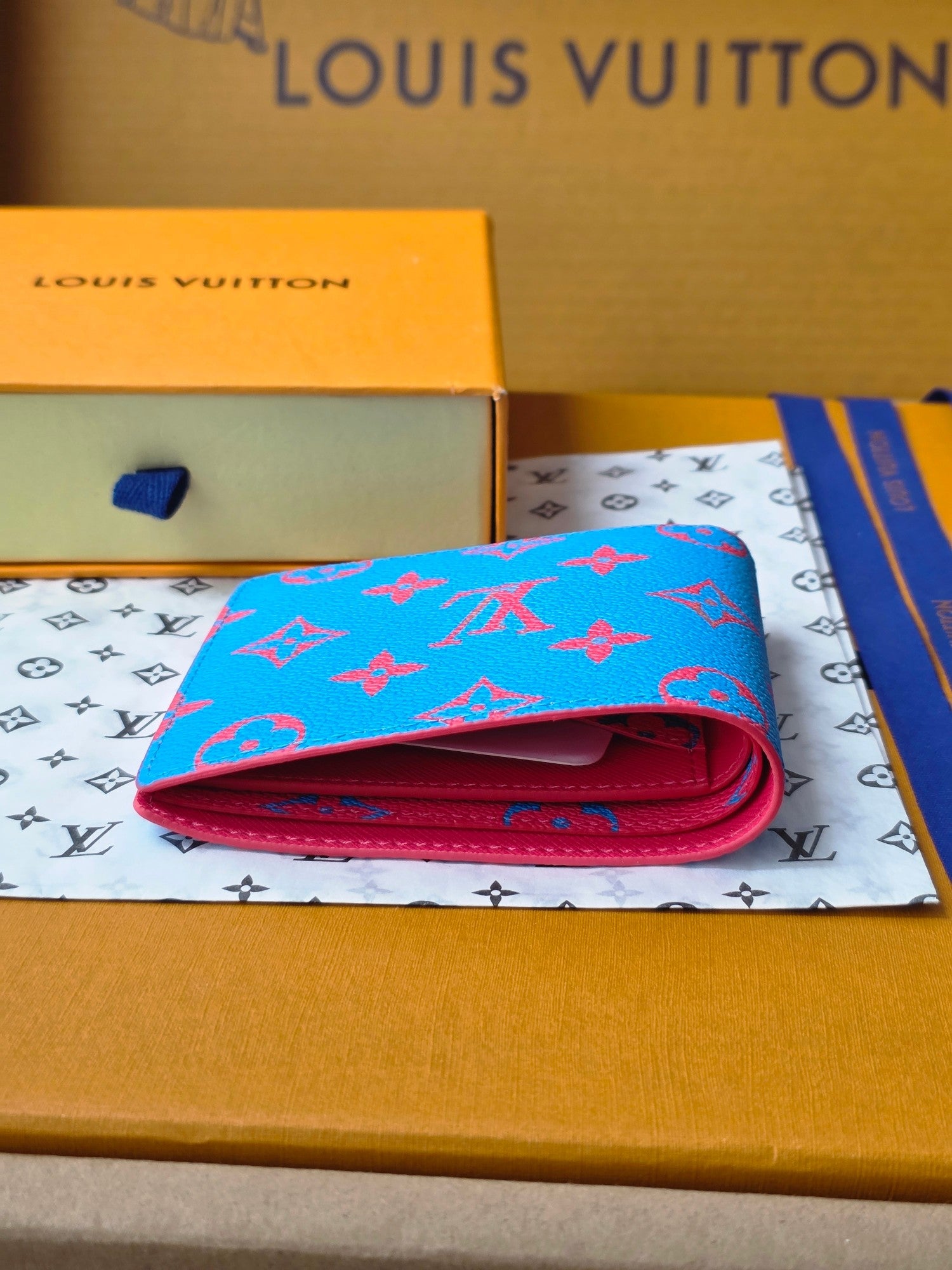 Small card wallet folded open, blue exterior with red fold and interior lining.