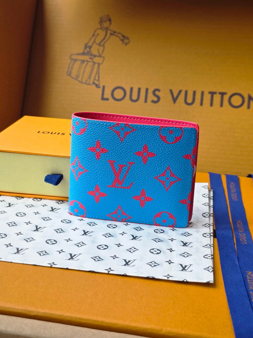 Small card wallet with blue monogram pattern, red trim, and fold-over front.