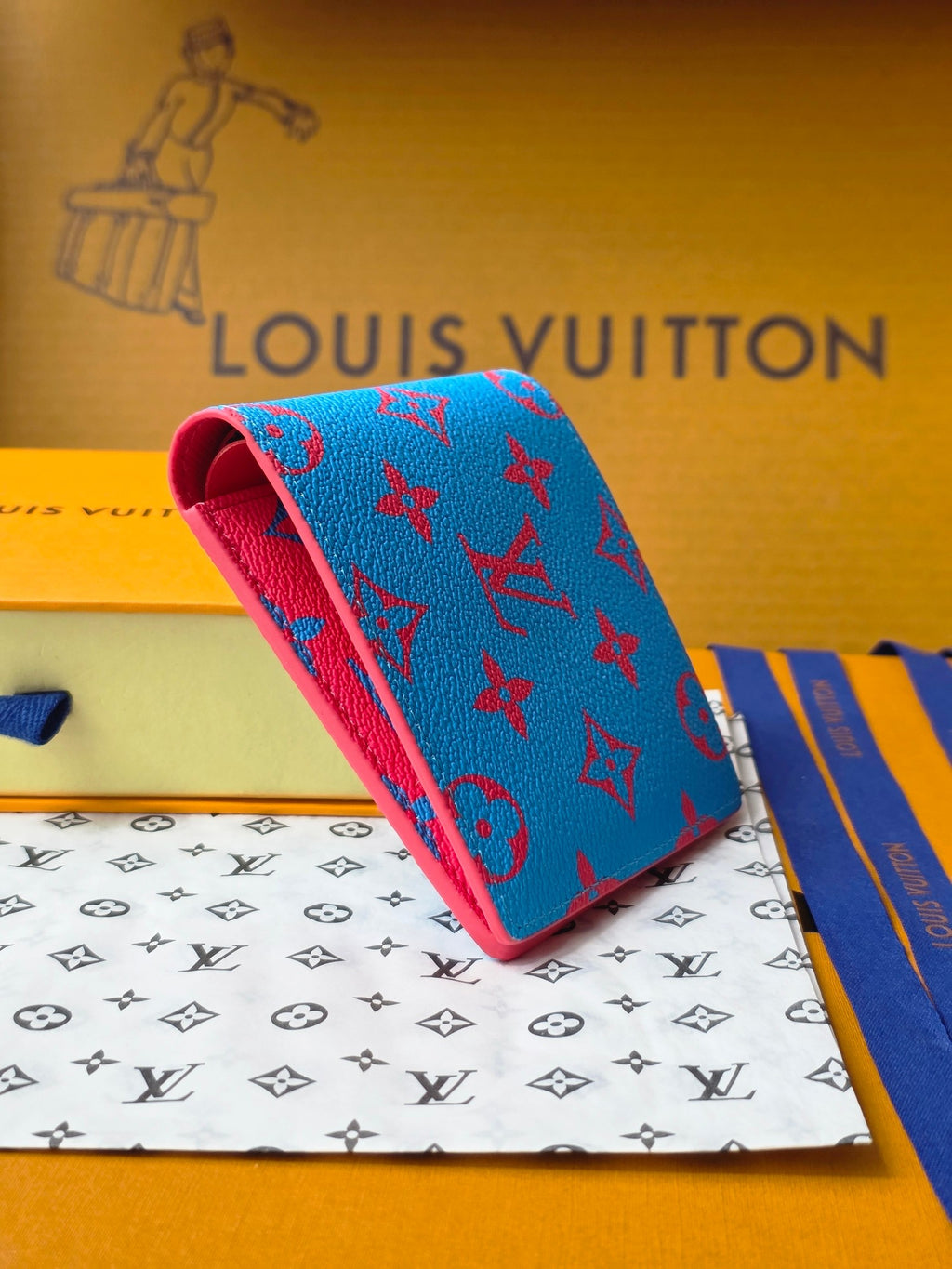 Small card wallet with blue patterned exterior and red underside, angled view.