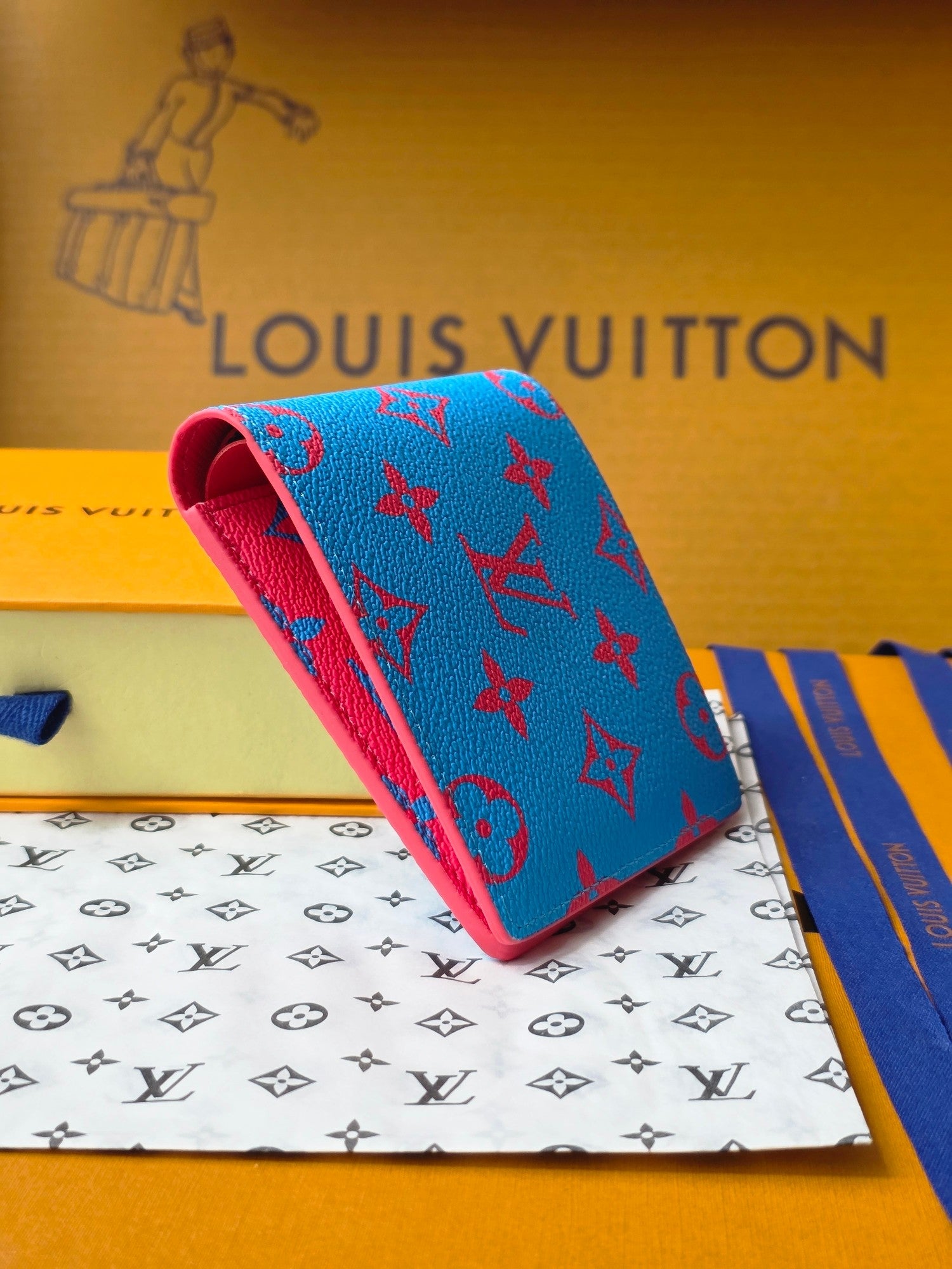Small card wallet with blue patterned exterior and red underside, angled view.