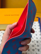Small card wallet profile view with blue monogram side and red inner lining.