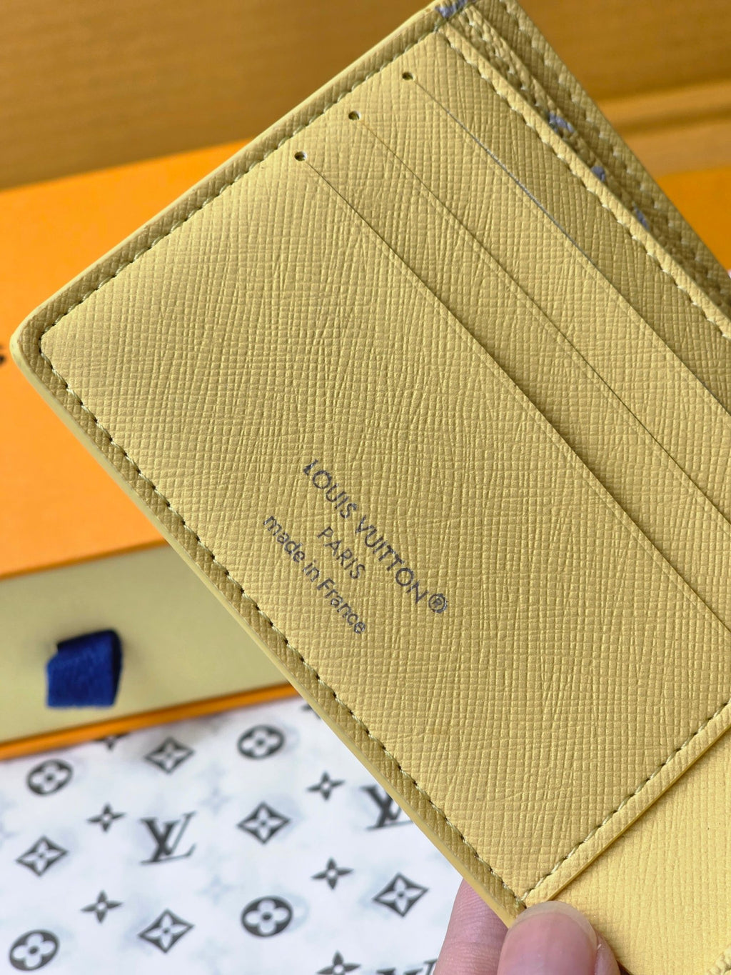 Small card wallet close-up of back, textured beige panel with Louis Vuitton text