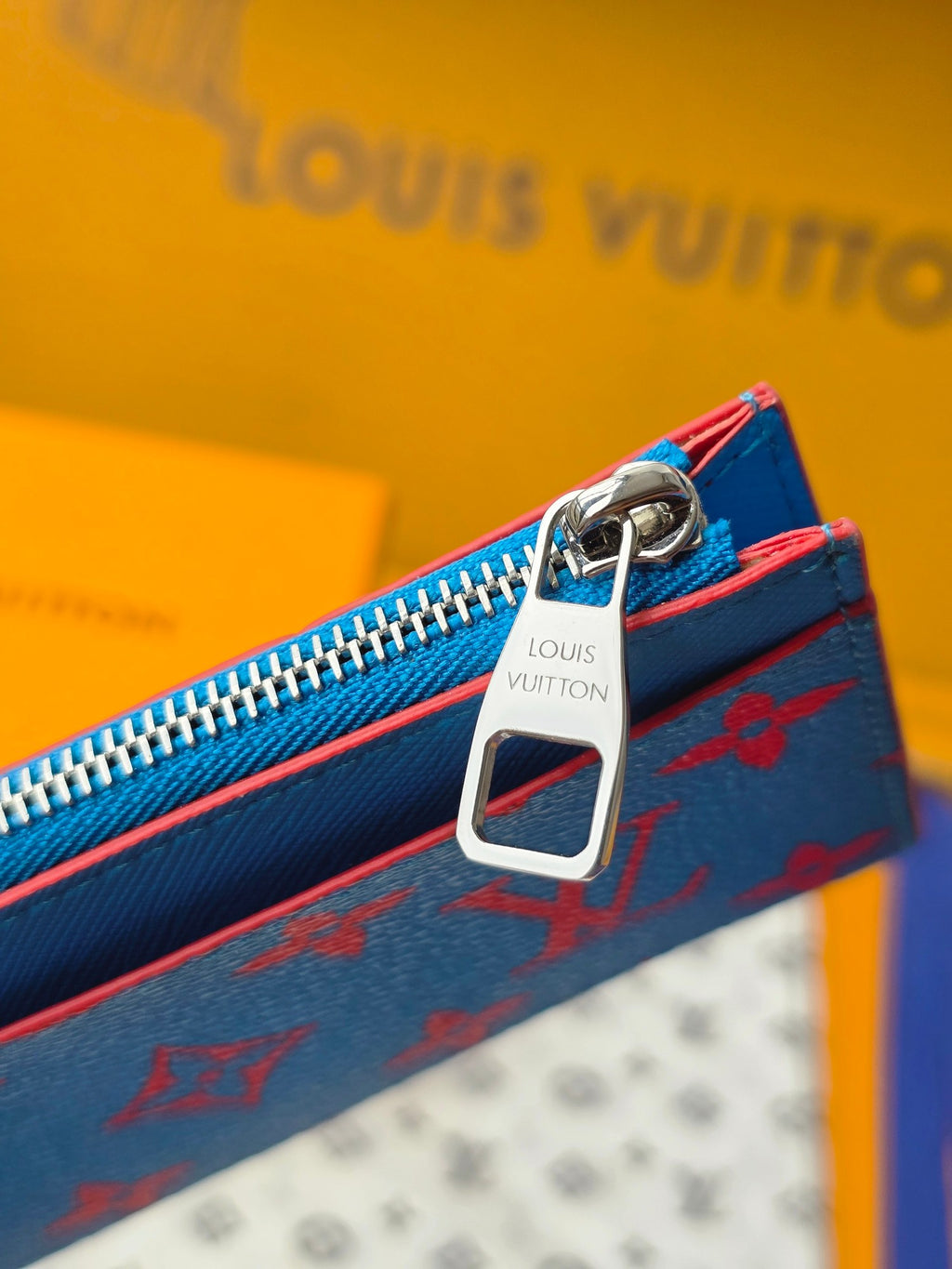 Small bag close-up of metal zipper pull and key ring, blue monogram side panel