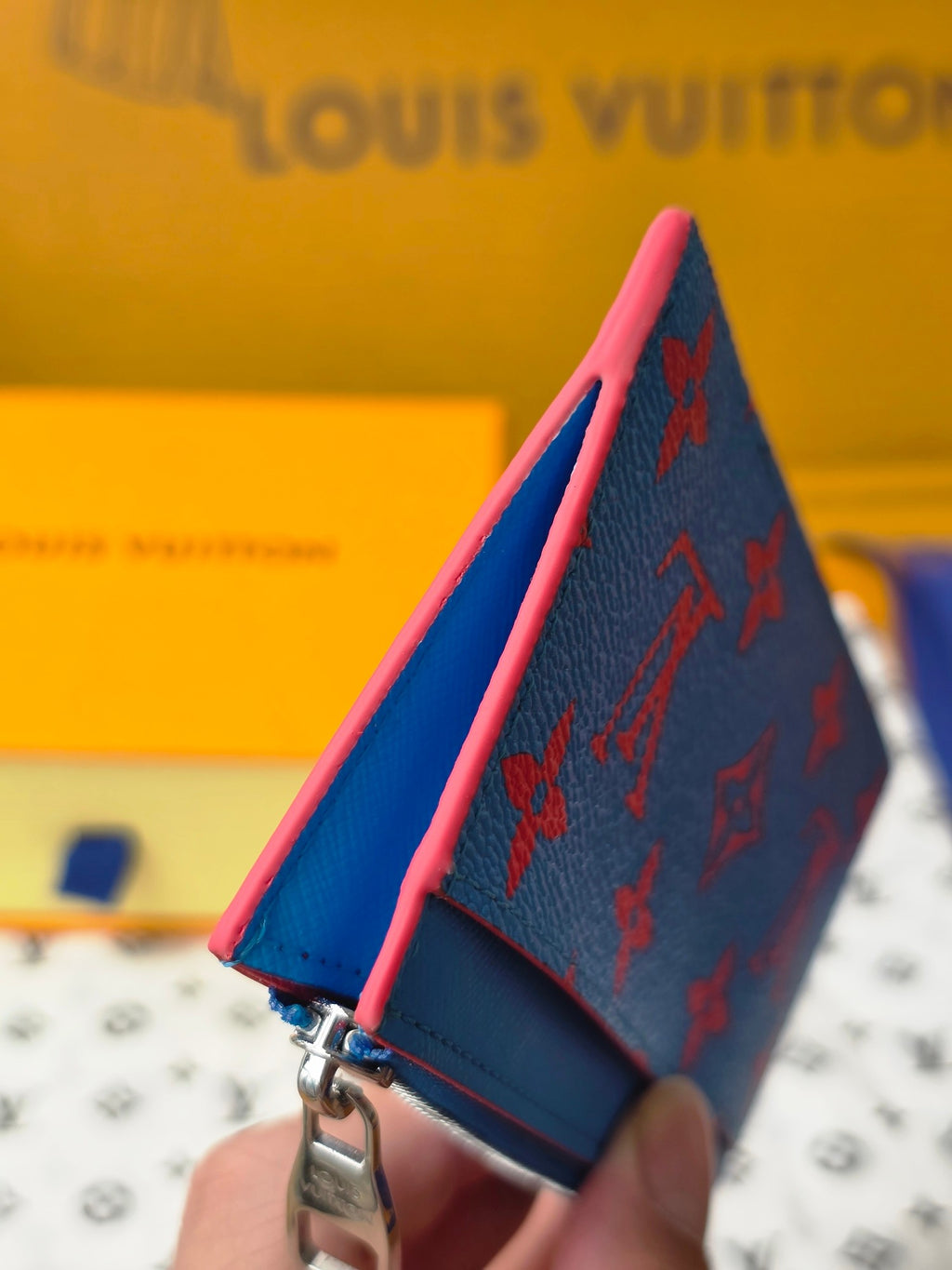 Small bag handheld view with blue exterior, pink trim edge, and metal clasp hardware