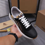 Black luxury sneaker held up: white laces, check collar, and stitched side panels