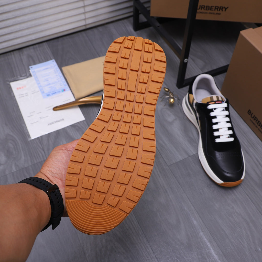 Luxury sneaker outsole view with textured orange-brown tread, black upper in frame
