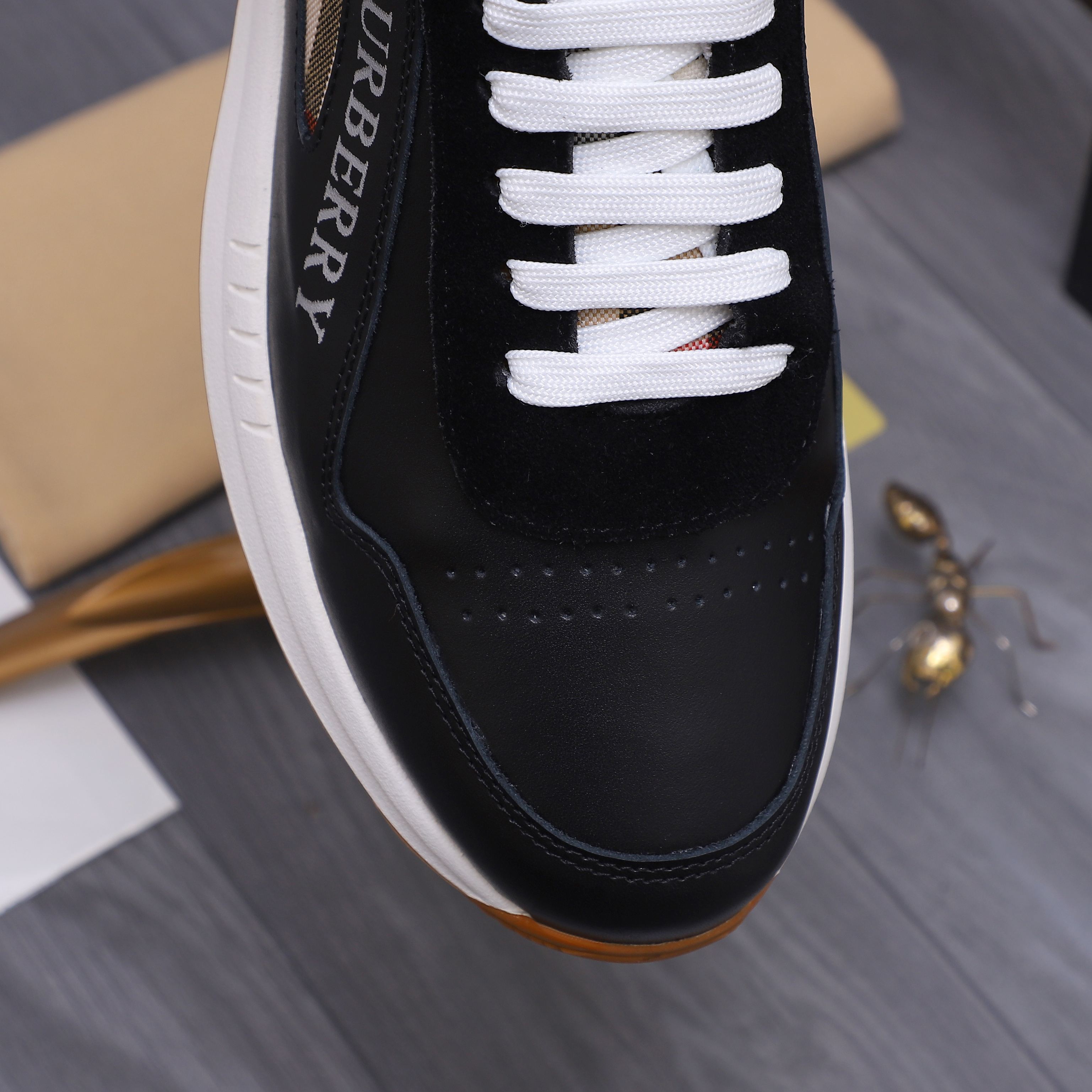 Close-up of black luxury sneaker side with white laces and contrast panel stitching