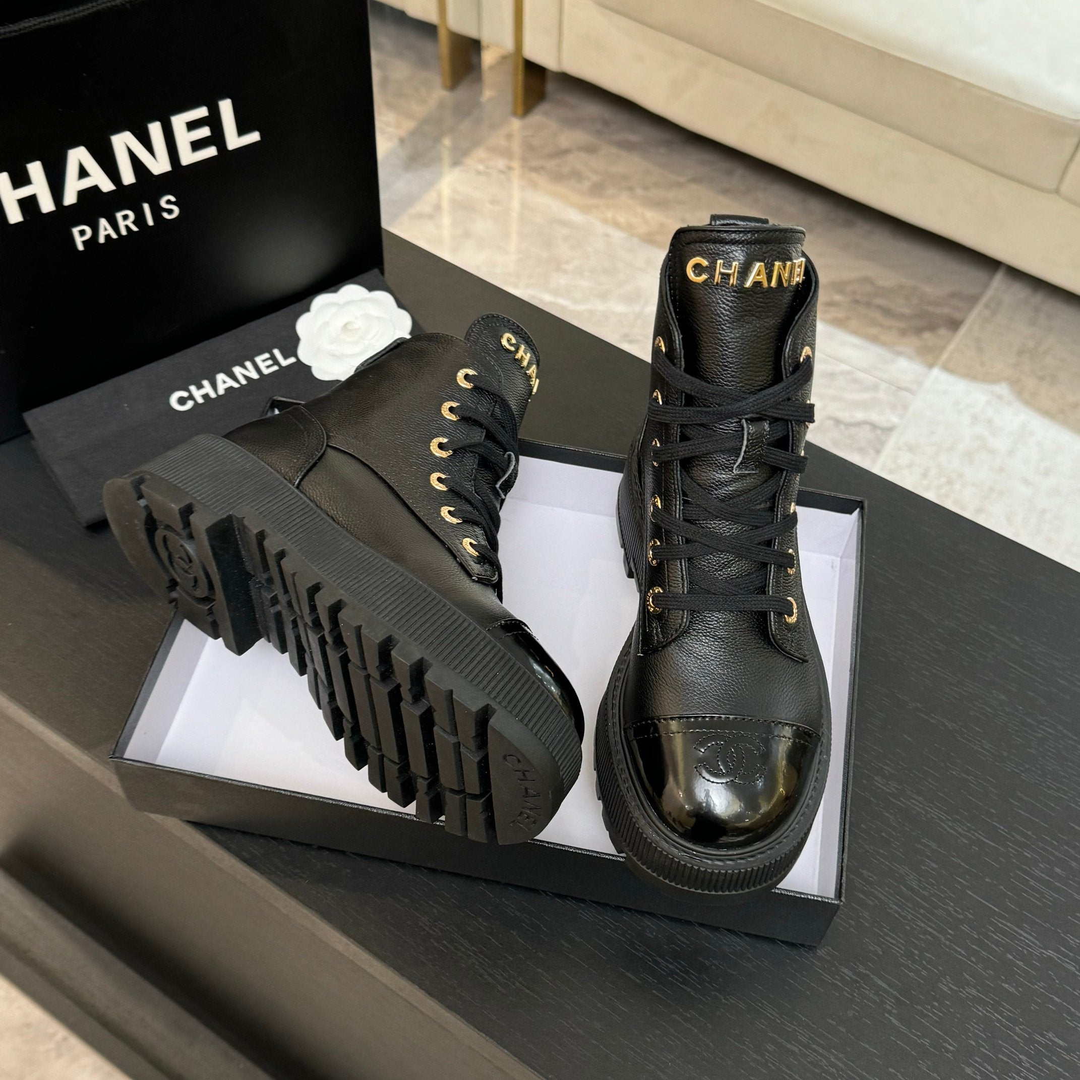 Black leather lace-up ankle boots with chunky tread sole, gold eyelets