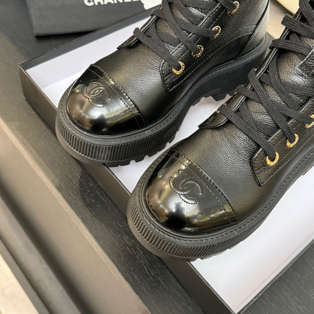 Black leather ankle boots close-up, gold-toned toe cap and lace eyelets