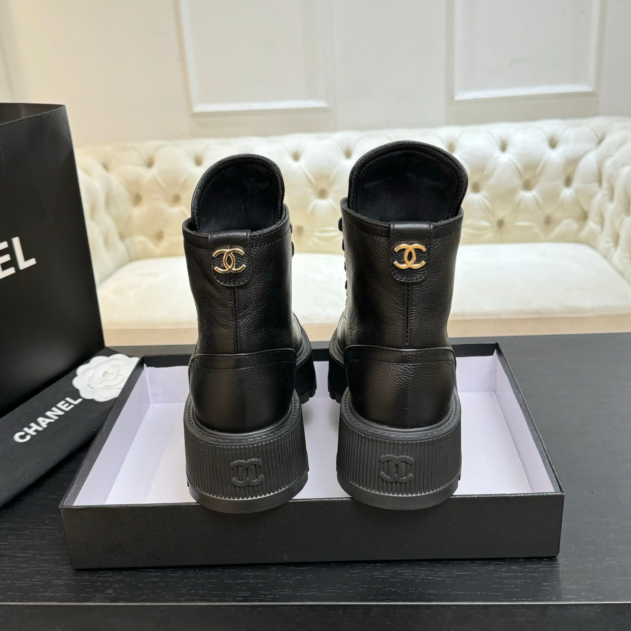 Black leather ankle boots with Chanel logo on heel and gold-toned emblem