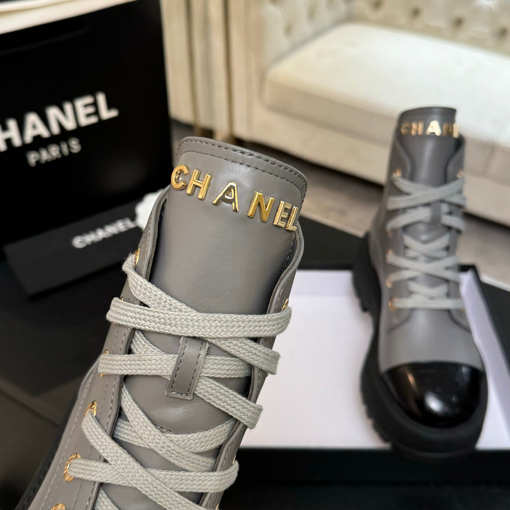 Chanel ladies high-top sneaker close-up, light gray upper with gold logo on tongue