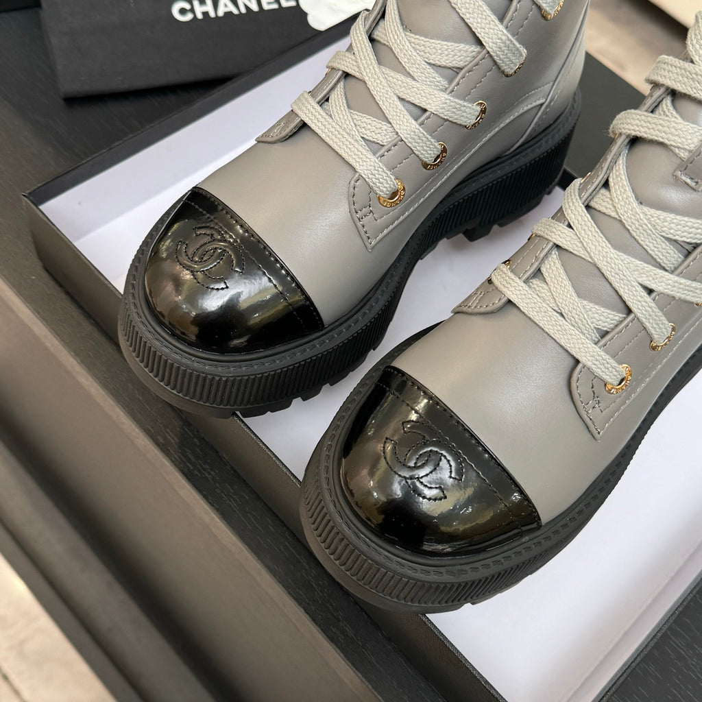 Chanel ladies high-top sneakers, close-up of gold logo toe caps on light gray leather