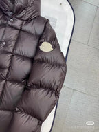 Moncler long puffer jacket sleeve and chest detail, dark quilted fabric, round logo patch