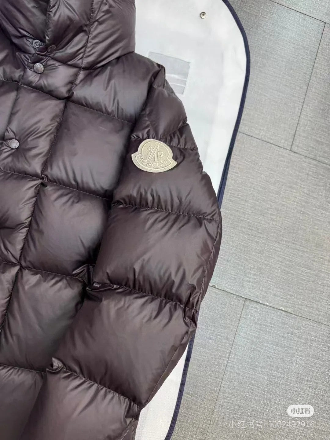 Moncler long puffer jacket sleeve and chest detail, dark quilted fabric, round logo patch
