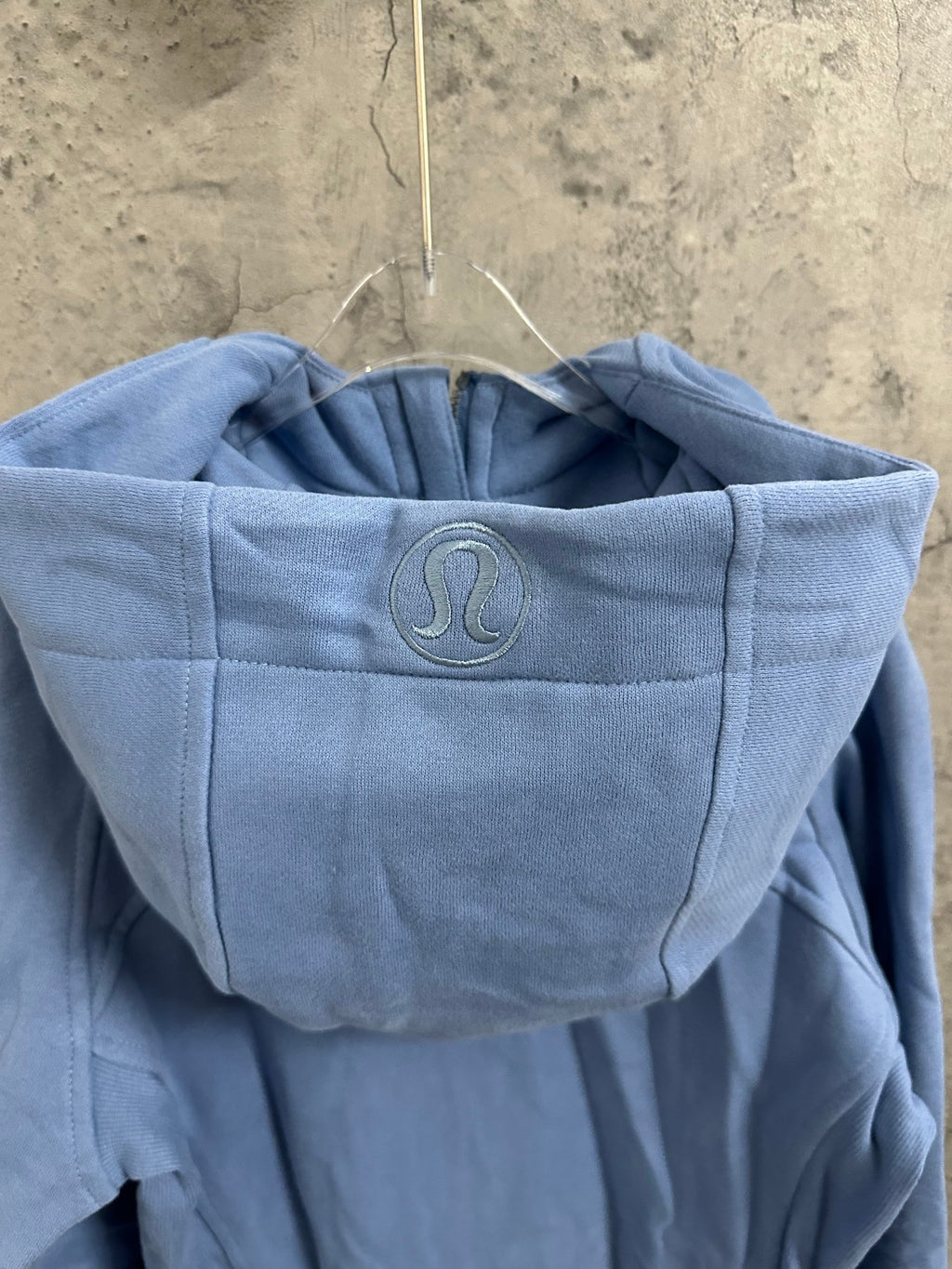 Light blue hooded sweatshirt with raised logo emblem on the hood