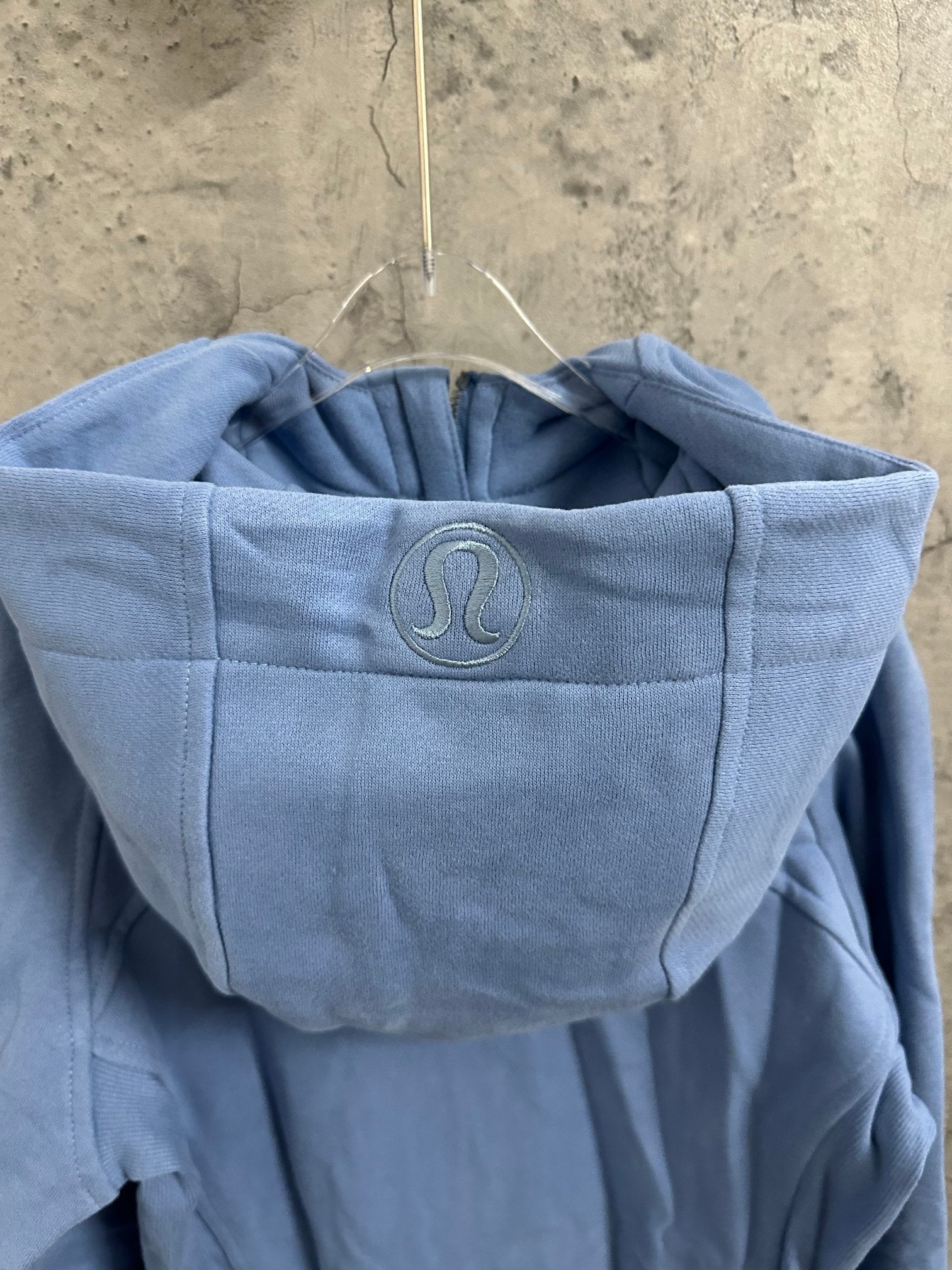Light blue hooded sweatshirt with raised logo emblem on the hood