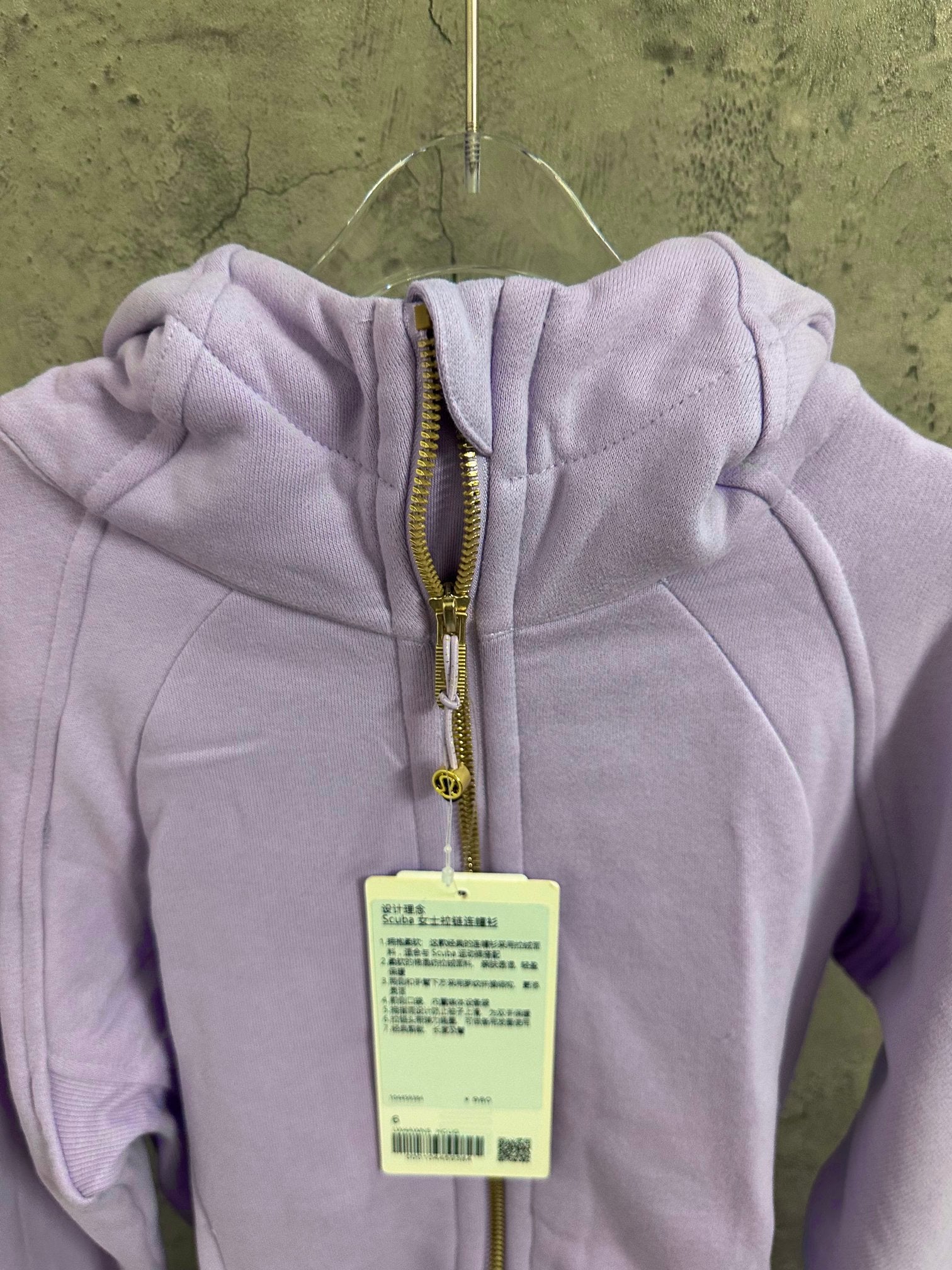 Light purple hoodie close-up: hood, front zipper, and hanging size tag