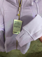 Light purple hoodie close-up with gold zipper and hanging size tag