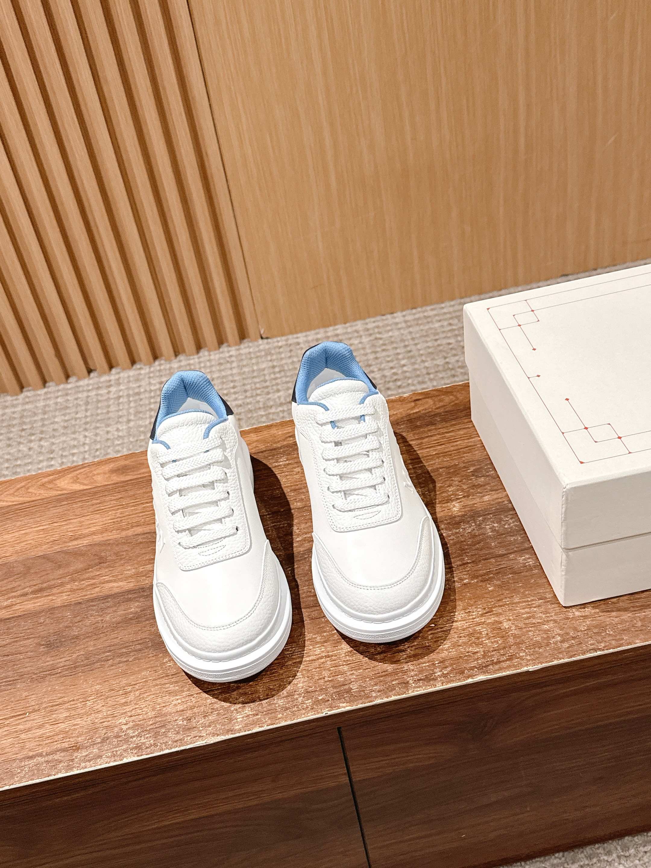 White leather low-top sneakers with blue inner lining, side by side.