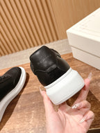 Black leather sneaker heel with white sole, held in a hand next to a box