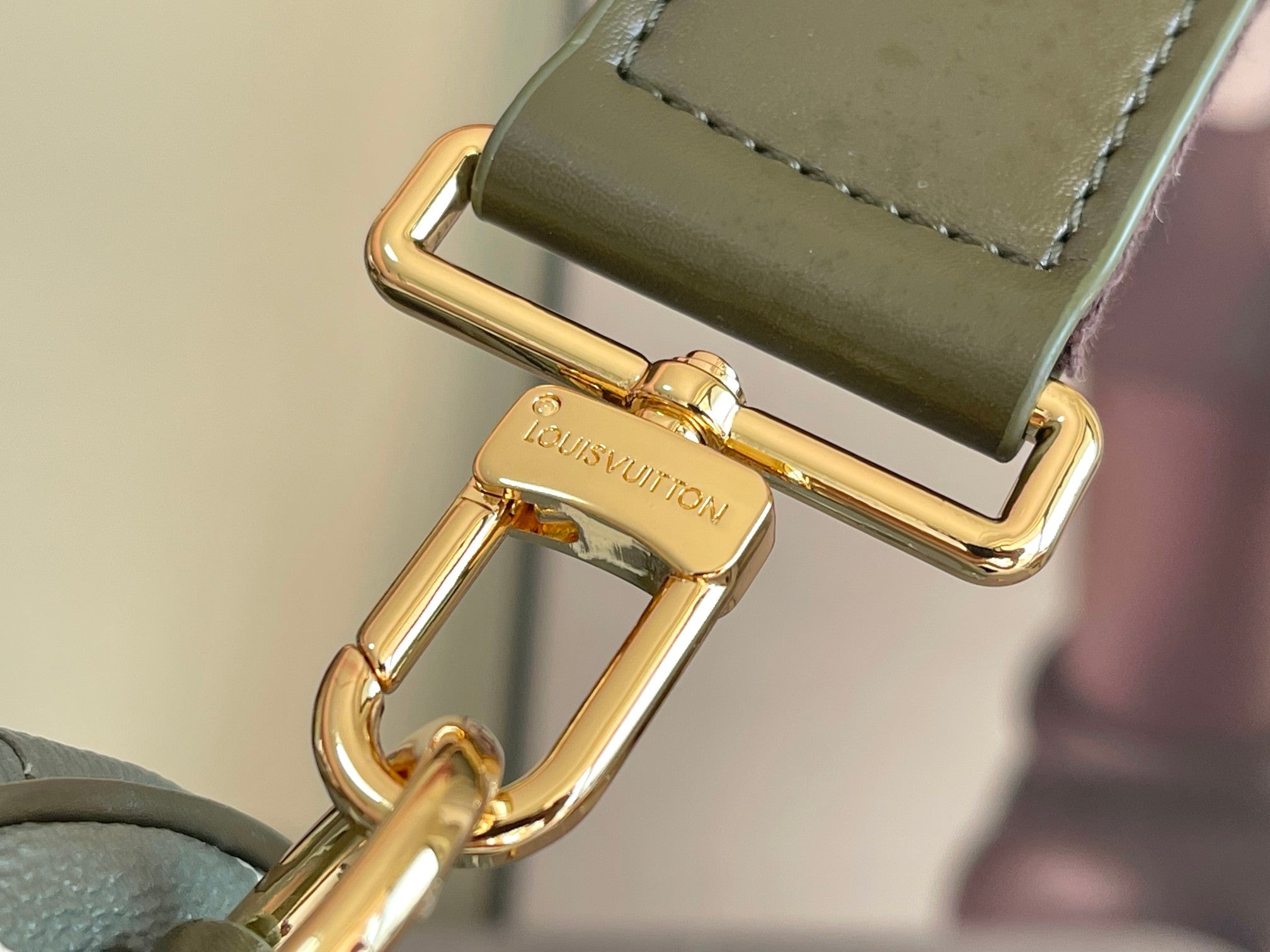 Dark green leather strap end with gold buckle clasp and embossed brand plate.