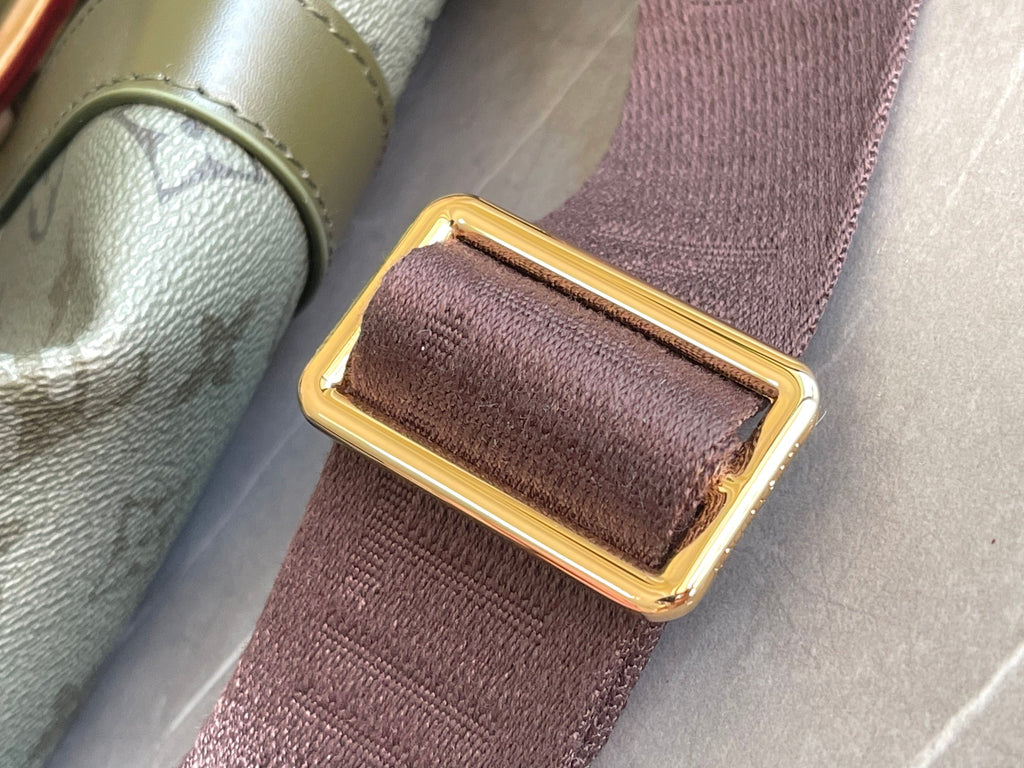 Brown fabric strap end with gold buckle hardware on a Louis Vuitton bag