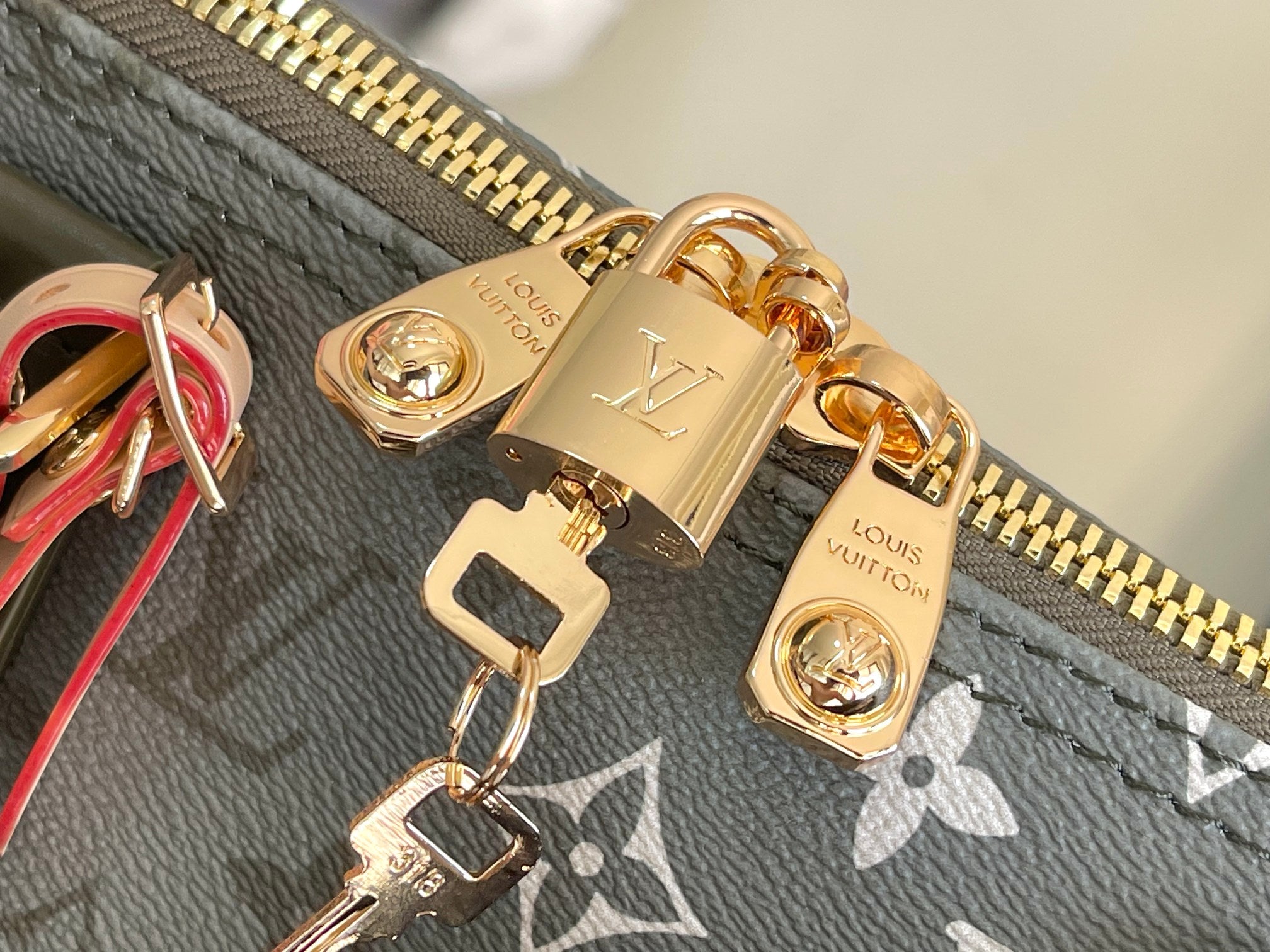Gold zipper pulls and padlock hardware on dark gray monogram canvas