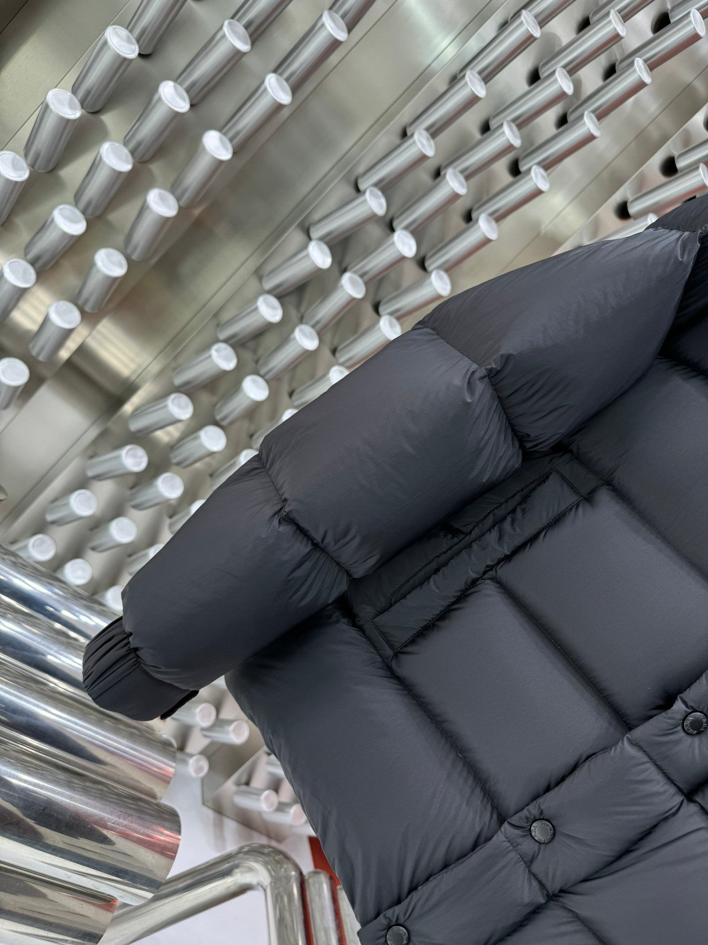 Long puffer jacket sleeve and lower back in dark gray with ribbed cuffs and buttons
