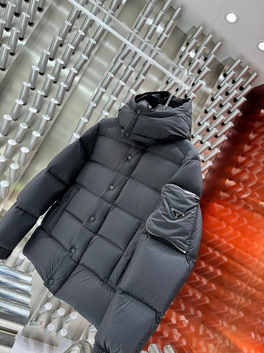Long puffer jacket in dark gray with hood and quilted design; sleeve pocket logo patch