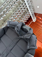 Long puffer jacket in dark gray with hooded collar, quilted panels, and button details