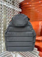 Back view of long puffer jacket in dark gray with padded hood and horizontal quilting