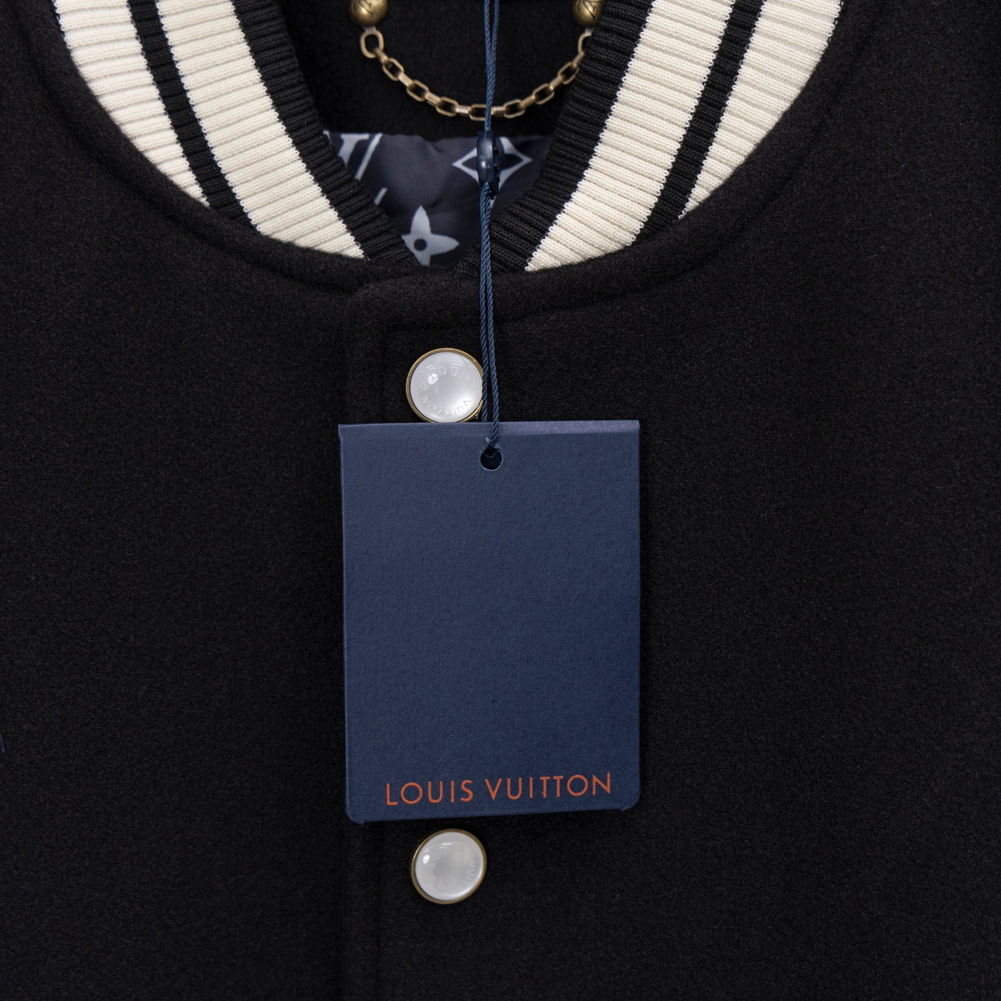 Black varsity jacket neckline with white stripes and hanging blue brand tag