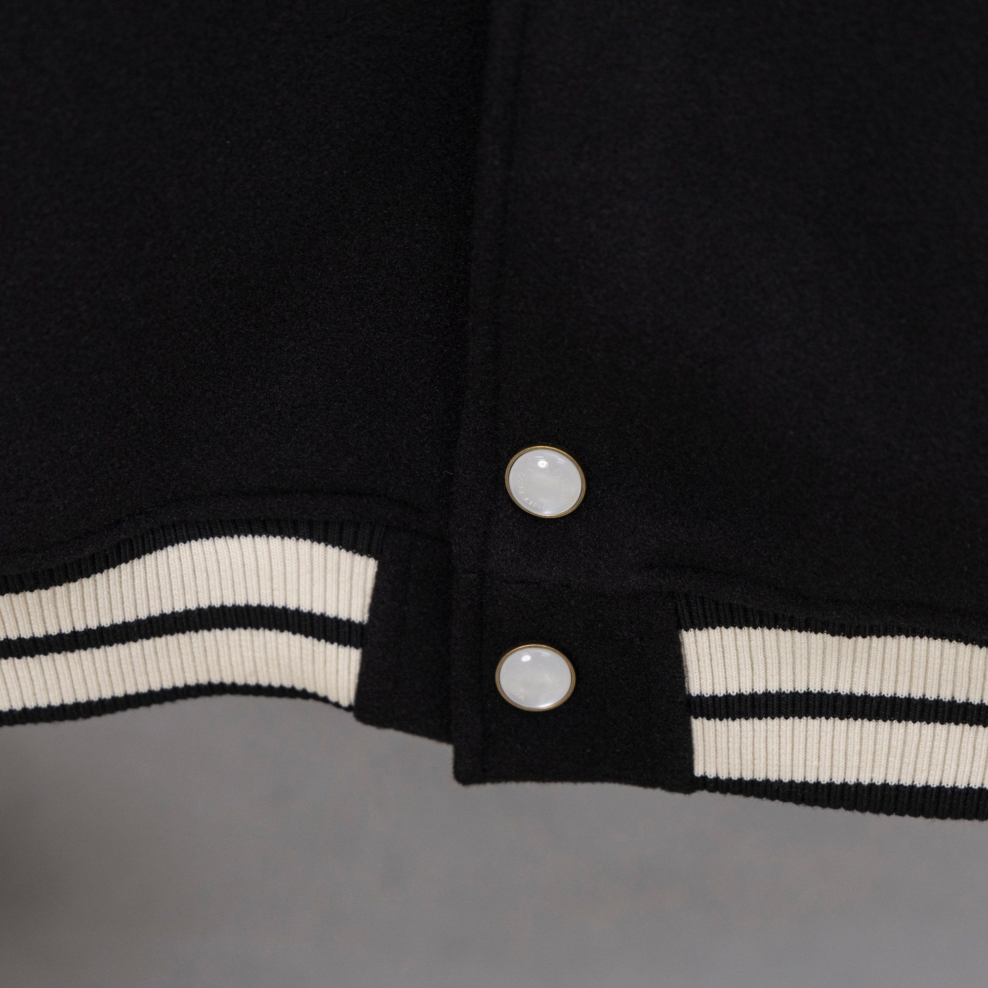 Black jacket hem with ribbed white-and-black stripe band and two snap buttons