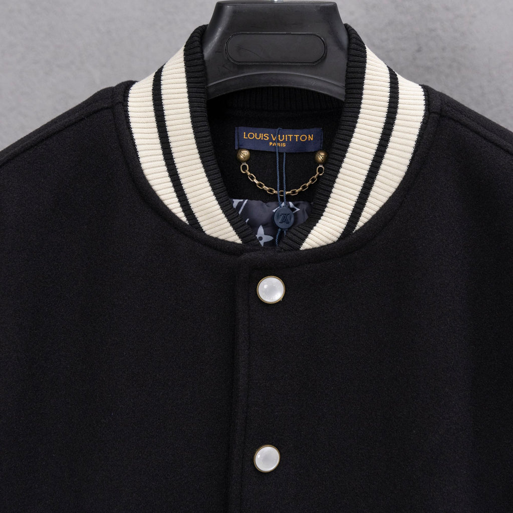 Black varsity jacket with striped collar, gold chain charm, and snap button