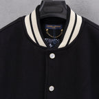 Black varsity jacket with striped collar, gold chain charm, and snap button