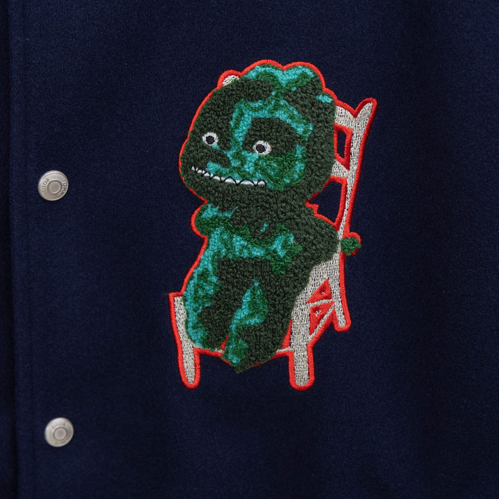 Dark navy jacket with embroidered green dinosaur patch and red-trim outline